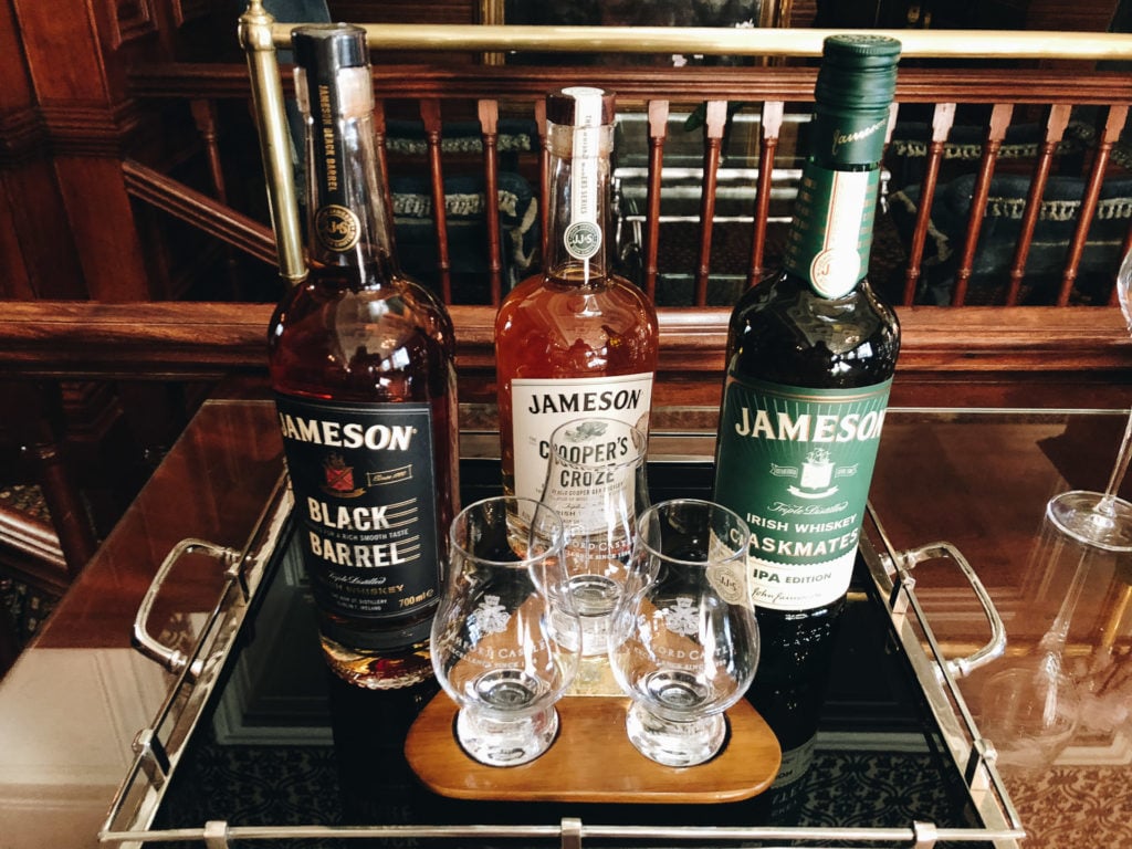 Three types of Irish whisky on a bar cart.