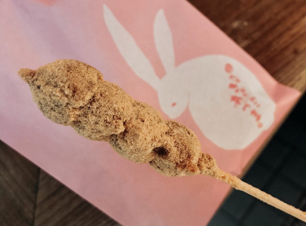A Japanese dessert called kinako dango (round sweet rice flour dumplings covered in a soy powder) with pink bunny wrapper in the background