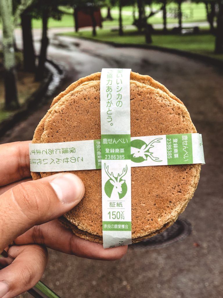 A hand holding a package of circular biscuits intended for deer in Nara, Japan