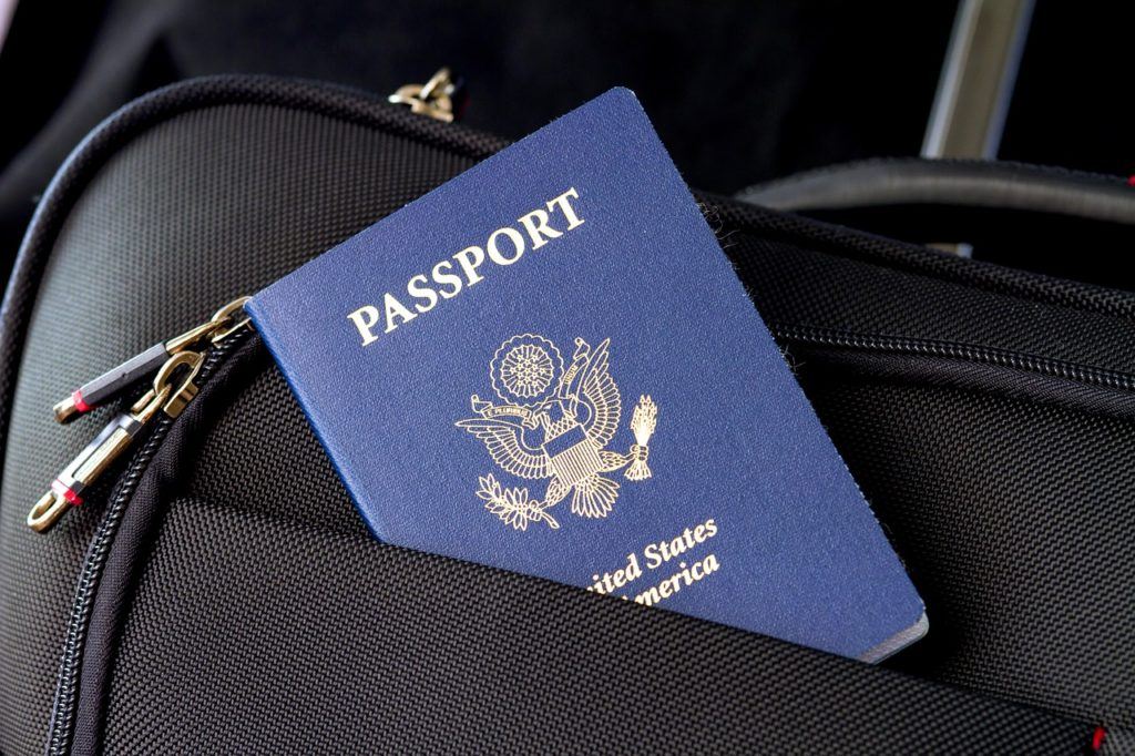 United States passport tucked inside the pocket of a black fabric covered suitcase.